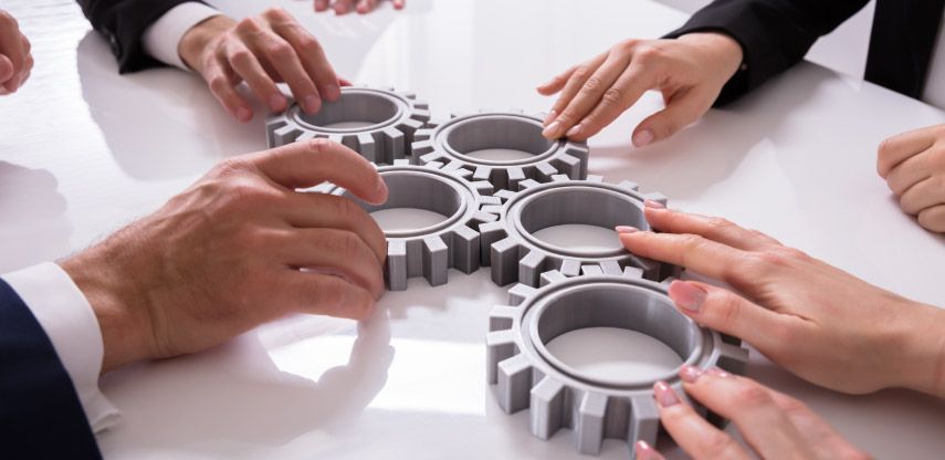 Gears in the hands of people at conference room table